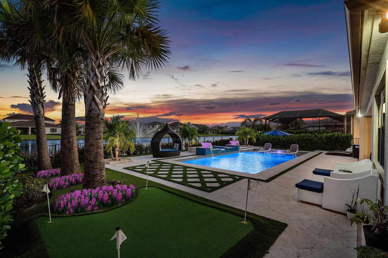 Luxury South Florida backyard with pool, palm trees and outdoor living space at sunset